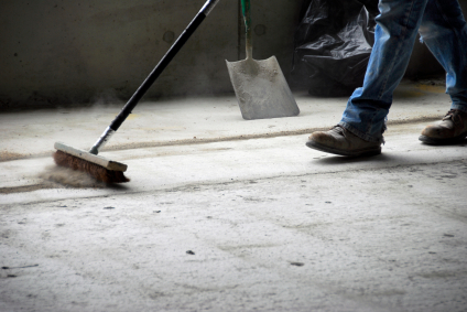 Sweeping up rough concrete flooring particles. Part of healthcare cleaning services is making sure all layers of flooring are spotless before final inspection.