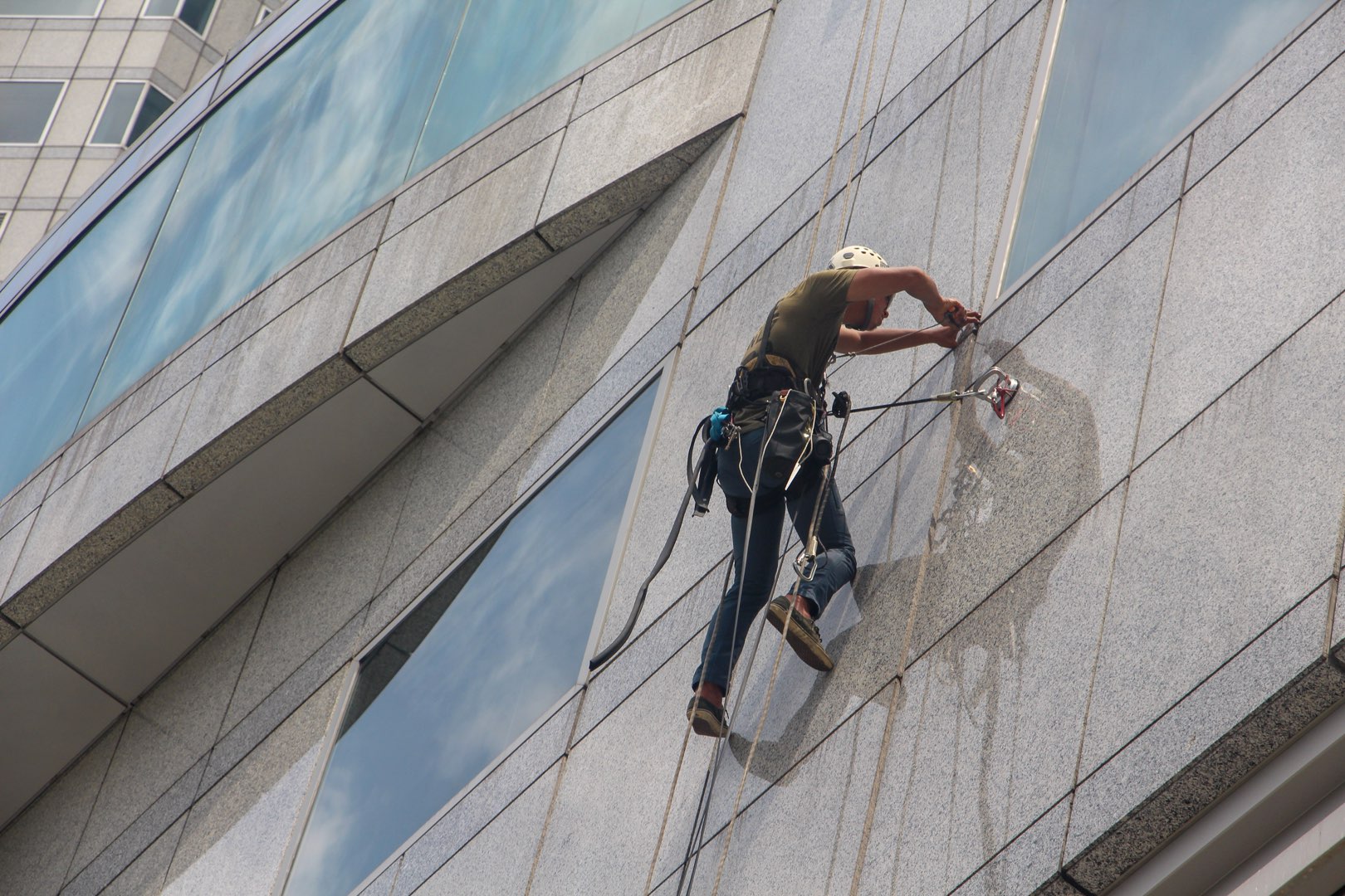 A window washer scales the outside of a building. Progressive Building Services also includes window cleaning.